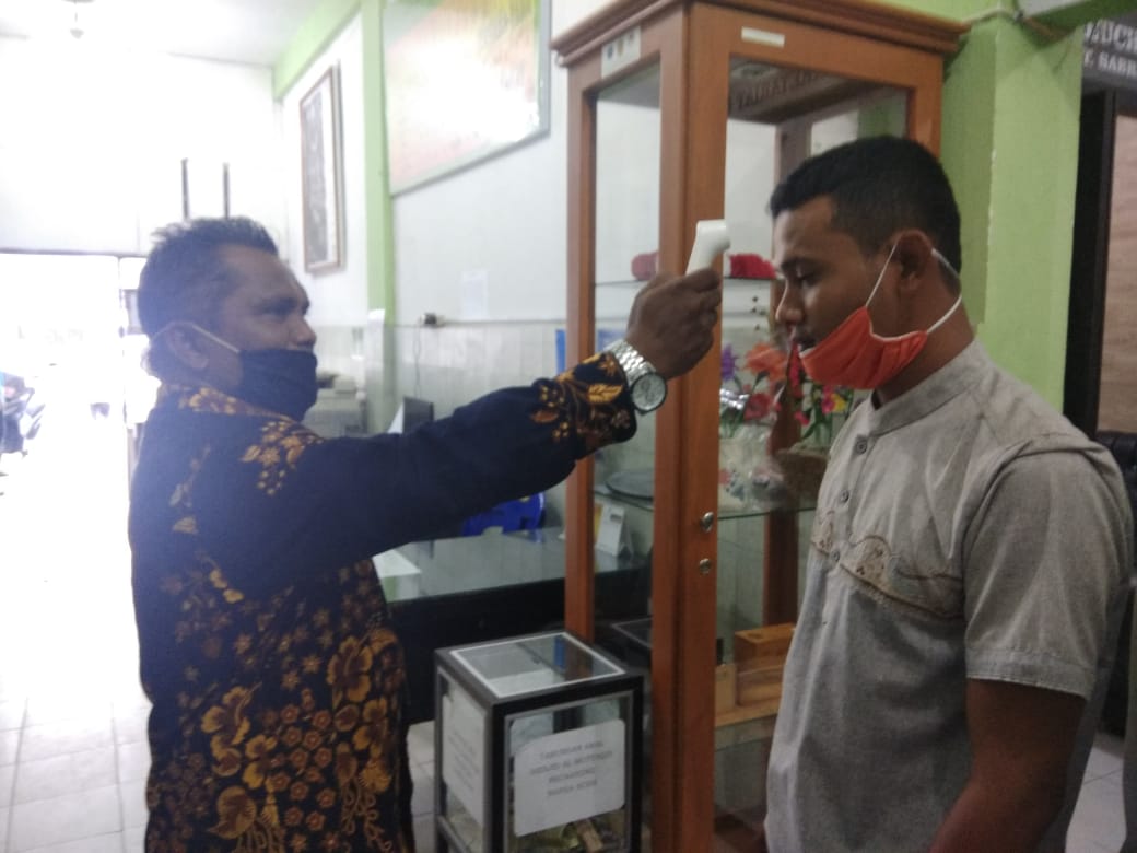 Keuchik Peunayong T. Sabri Harun, S. Ag. sedang melakukan pengecekan suhu kepada Ulee Jurong Garuda Agus Taufik di Kantor Keuchik Gampong Peunayong.